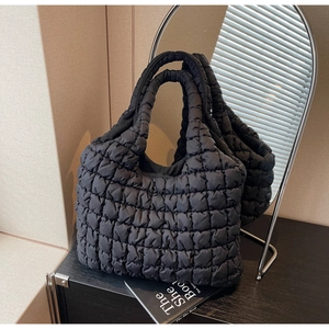Close-up of black quilted bubble tote bag texture with 3D plaid pattern and wide handles