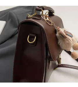 Detail of dark brown vintage square bag featuring golden hardware and plush bear charm