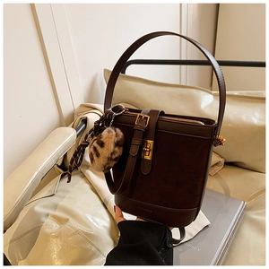 Detailed close-up of a vintage brown bucket bag featuring a leopard fur charm and gold lock