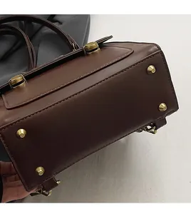 Detail view of dark brown bag bottom featuring four protective gold metal rivets