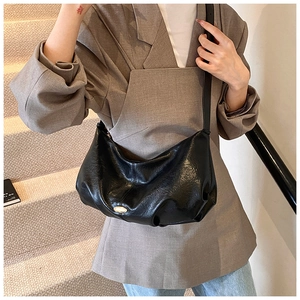 Détail d'un sac demi-lune noir en similicuir avec boucle dorée et design plissé chic
