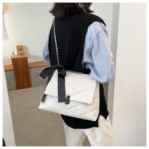 Détail du sac cabas matelassé blanc avec chaîne argentée et un grand nœud décoratif noir