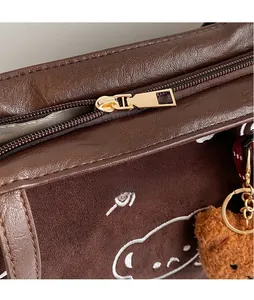 Detail of the golden metal zipper and suede texture on a chocolate brown tote bag