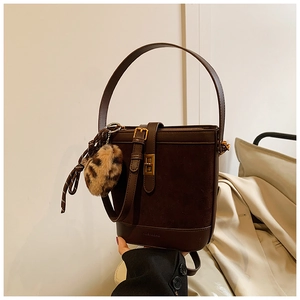 Detail of vintage brown bucket bag showing suede texture and leopard print pompom