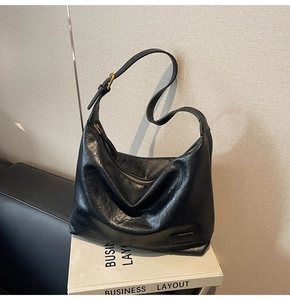 Dettaglio della borsa tote in ecopelle nera con fibbia metallica e tracolla regolabile