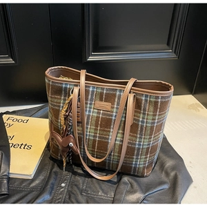 Detailed view of checkered wool tote bag with leather trim and animal-shaped pendant