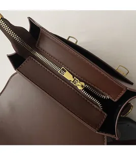 Detailed close-up of smooth metal zippers and stitching on a vintage brown backpack
