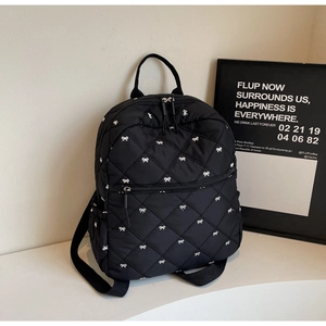 Détail du sac à dos matelassé noir avec broderie de nœuds et poche avant zippée