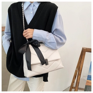 Détail du sac cabas matelassé blanc avec nœud noir et bandoulière chaîne sur modèle