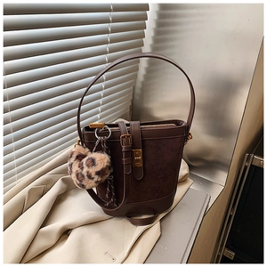 Detail of vintage brown bucket bag with gold clasp and leopard plush pendant accessory