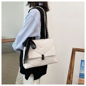 Détail d'un sac cabas en cuir matelassé blanc avec nœud noir et chaîne argent