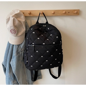 Détail d'un sac à dos noir matelassé avec broderie nœud suspendu à un crochet