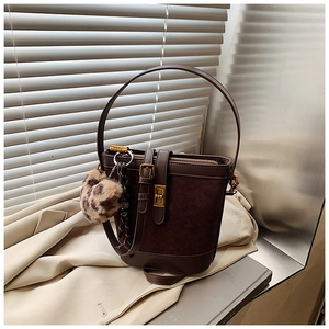 Detail of dark brown suede bucket bag with metal twist lock and leopard print charm