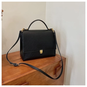 Detail of classic black lychee grain leather handbag with gold metal square lock
