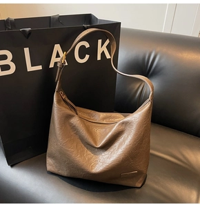 Dettaglio ravvicinato della borsa in pelle marrone scuro con cerniera e fibbia dorata
