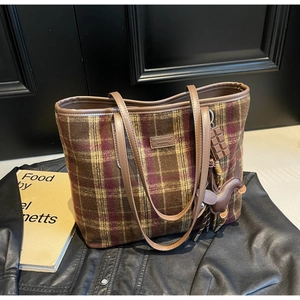 Macro detail of plaid tote bag with brown leather label and dachshund bag charm