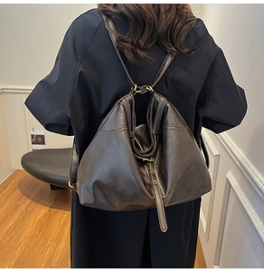 Dunkelbrauner Kunstleder-Tragerucksack am Modell in einem minimalistischen Raum gezeigt