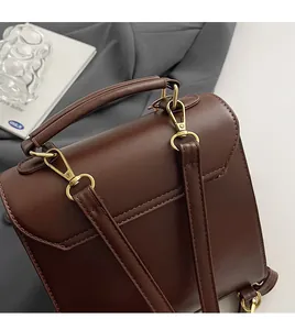 Detail of vintage brown leather backpack showing detachable metal hooks and top handle