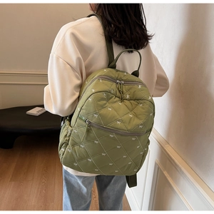 Détail du sac à dos matelassé vert herbe avec motifs nœuds blancs et poches multiples