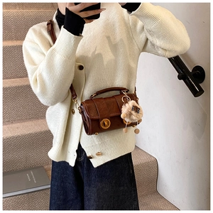 Details einer braunen Vintage-Lederhandtasche mit Goldverschlüssen und Bärenanhänger