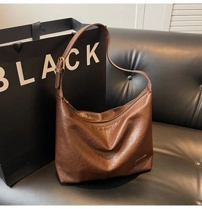 Dettaglio della borsa a tracolla vintage marrone scuro su un divano nero