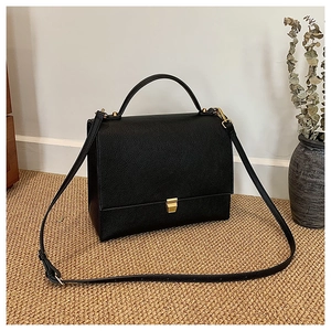 Detail of black lychee grain leather crossbody bag with elegant gold metal buckle