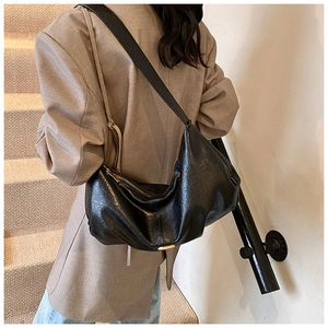 Détail du sac dumpling en cuir noir avec zip doré et design plissé élégant