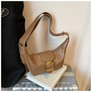 Dettaglio di una borsa a mezzaluna marrone in pelle martellata con finiture in metallo oro