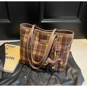 Detail of plaid tote bag with brown leather straps and cute chocolate dog charms