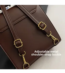 Detail of dark brown leather bag with adjustable gold hardware buckles and neat stitching