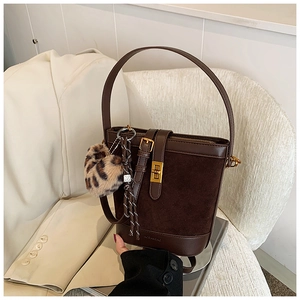 Detail of dark brown bucket bag featuring gold hardware and leopard faux fur charm