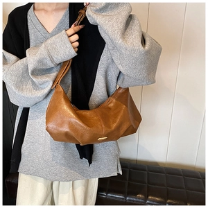 Détail du sac bandoulière en similicuir marron souple avec une boucle en métal doré