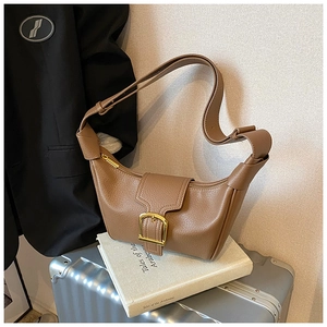 Dettaglio borsa marrone in pelle martellata con fibbia dorata e tracolla con nodo