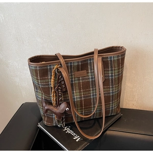 Detail of plaid tote bag featuring leather Teddy Bear patch and brown animal charm