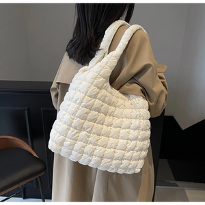Detail of quilted white tote bag featuring soft padded texture and shoulder strap design