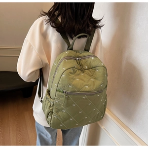 Détail d'un sac à dos en nylon vert matelassé avec broderie et poche latérale de rangement