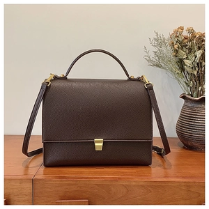 Close-up of dark brown lychee grain leather handbag with elegant gold metal buckle