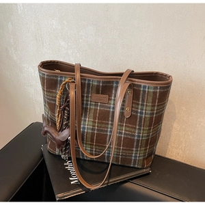 Detail of checkered tweed tote bag with leather trim and decorative horse charm