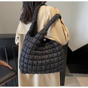 Detailed view of the black quilted puffer shoulder bag with soft textured grid pattern