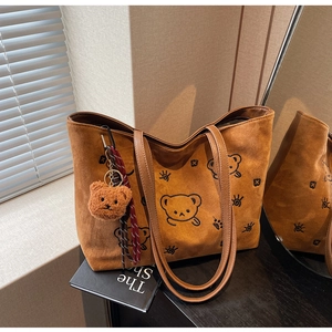 Detailed view of brown suede tote bag featuring a cute bear print and plush charm