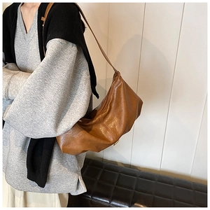 Sac demi-lune marron en similicuir porté par un mannequin au style vintage minimaliste