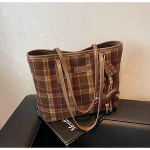 Detail of wool tote bag with plaid pattern, leather logo tag, and cute puppy charms
