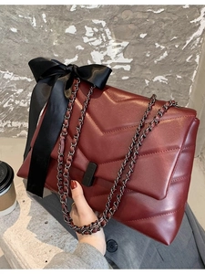 Sac à bandoulière matelassé en V bordeaux avec chaîne noire et breloque noeud papillon