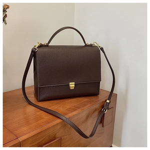 Detail of dark brown leather crossbody bag with vintage texture and gold buckle