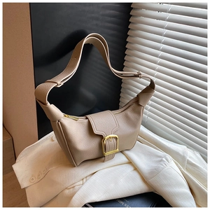 Dettaglio della borsa a mezzaluna beige in pelle con fibbia dorata lucida