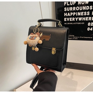 Detail of black faux leather backpack with dachshund embroidery and plush charm accessory