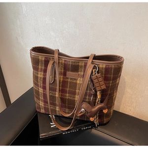 Detail of checkered tote bag featuring leather handles and a chocolate shape pendant