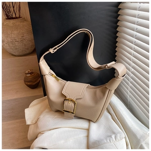 Dettaglio borsa hobo beige in pelle martellata con fibbia dorata su blazer bianco