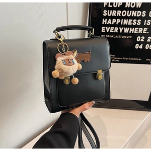Detail of black leather mini square bag with dachshund embroidery and teddy bear charm