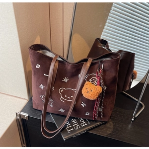 Detailed macro of suede tote bag with white bear pattern and plush bear charm
